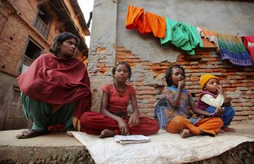 pexels-photo-11576242-11576242 Family sitting against a brick wall in an urban neighborhood, showcasing vibrant clothing and a sense of community.